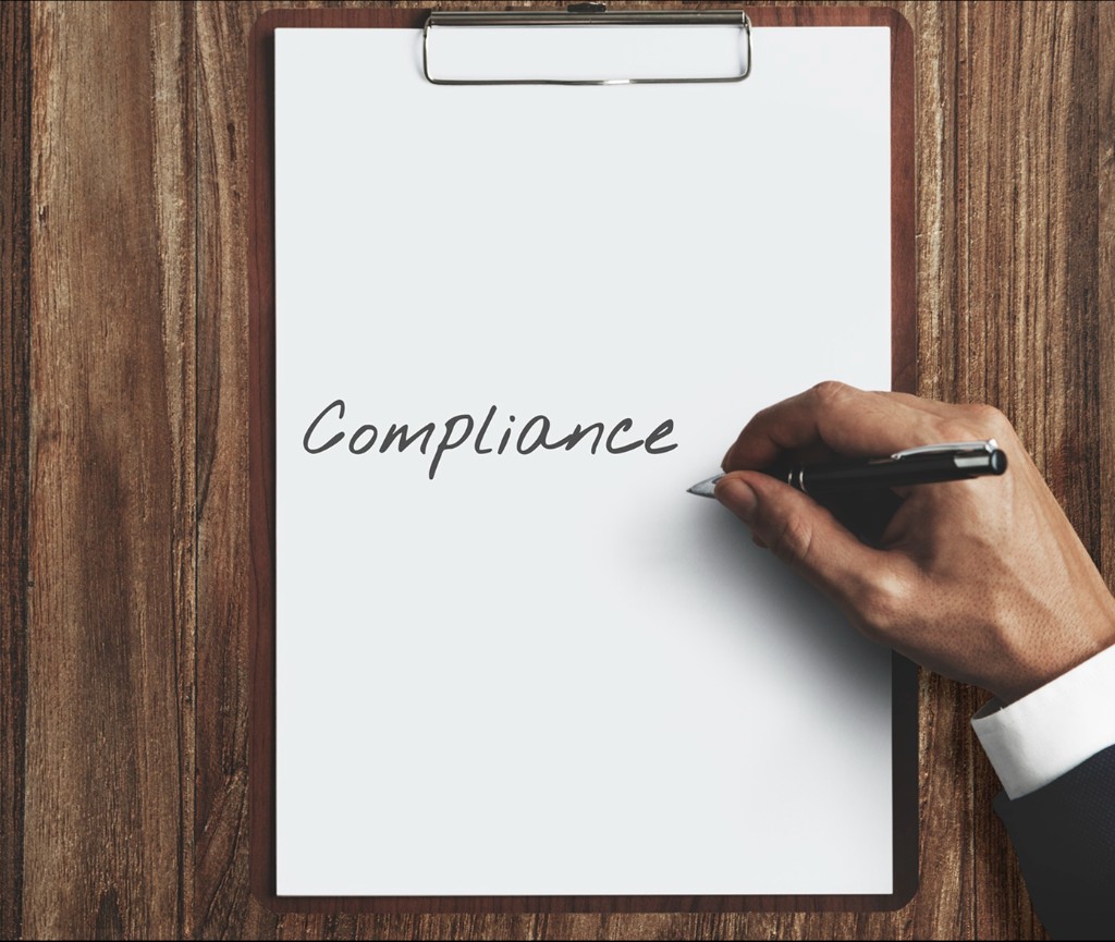 Hand writing Compliance on a clipboard
